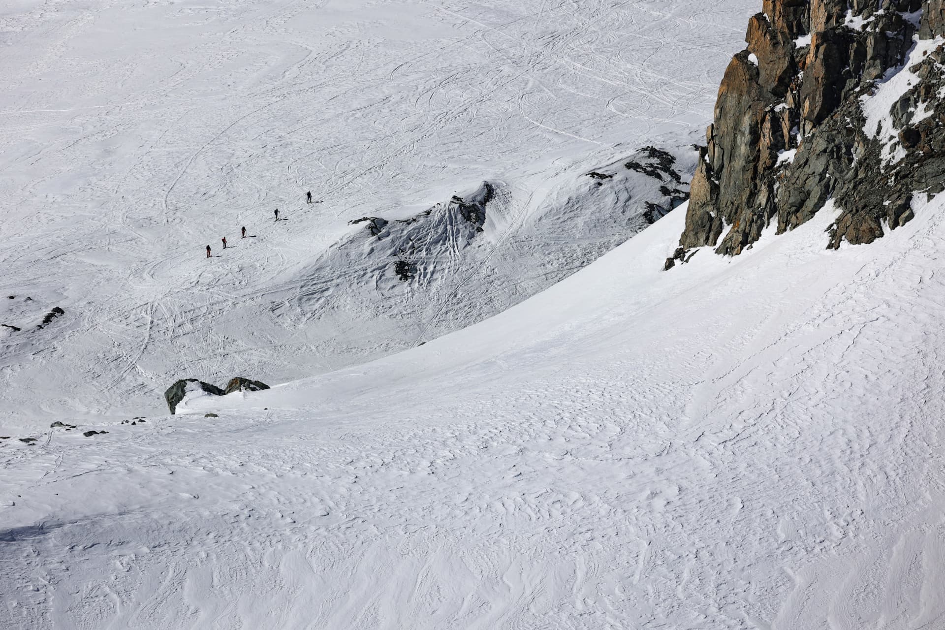 Skitourengruppe im Aufstieg über den Gletscher unter der Felswand