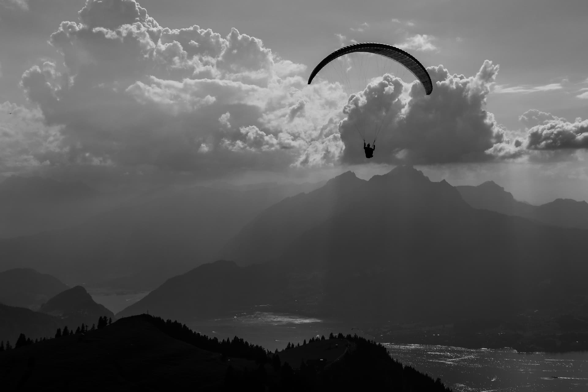 Schwarzweissfoto eines Gleitschirms über dem Rigi-Grat und den Wolken