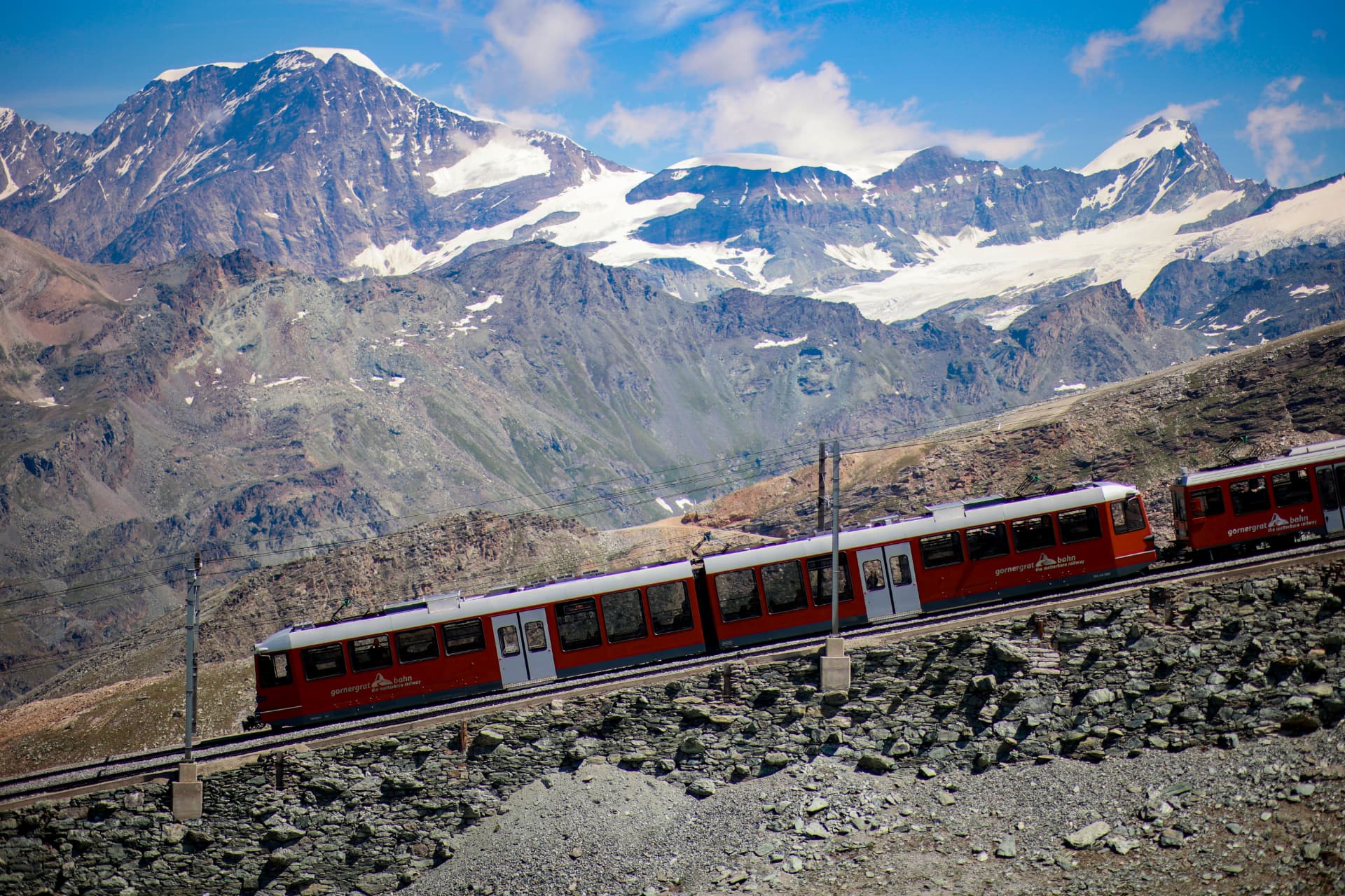 Roter Zug der Gornergratbahn vor verschneiten Gipfeln