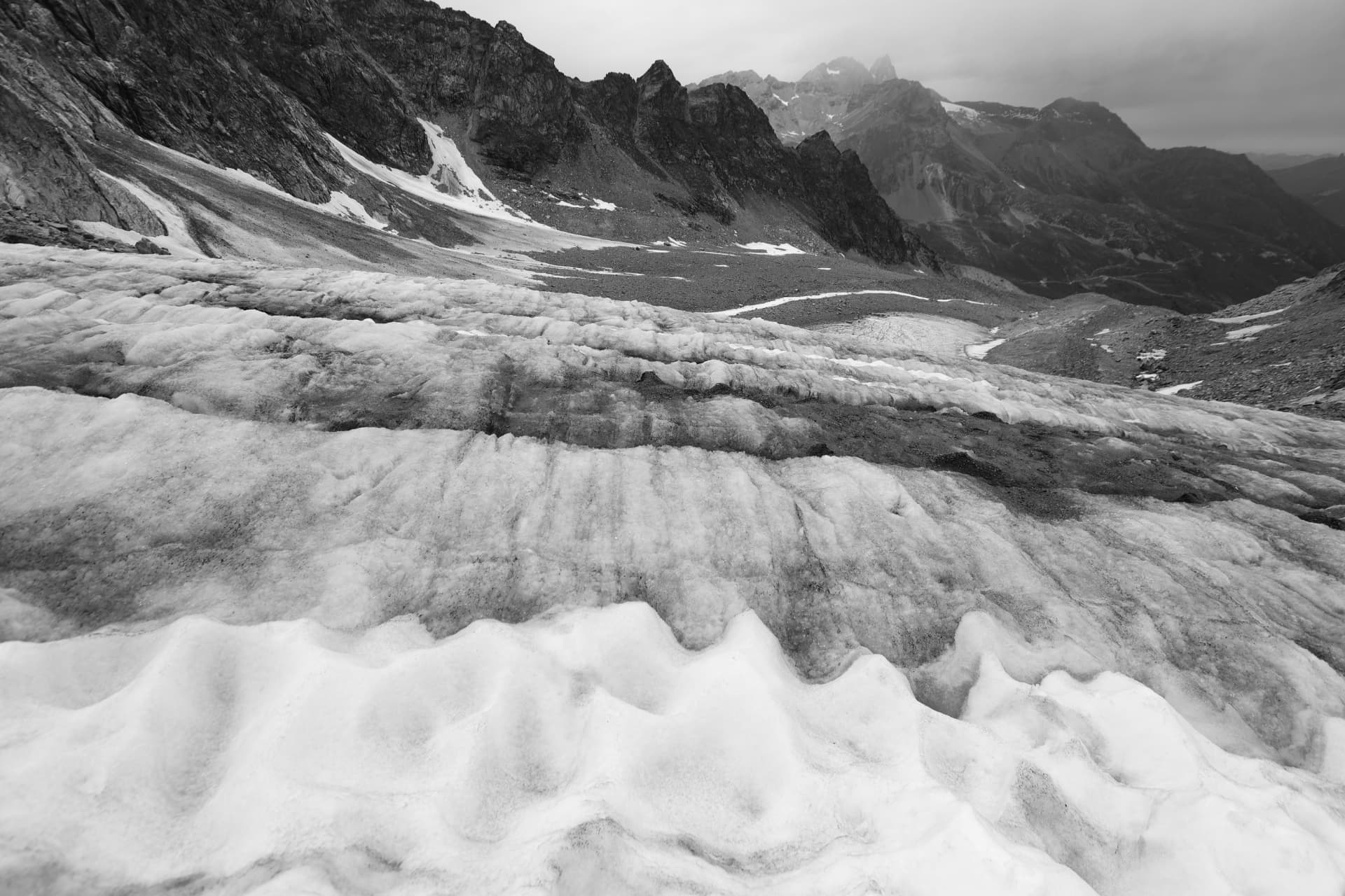 Schwarzweisse Aufnahme der Gletscheroberfläche und scharfer Gipfel im Nebel