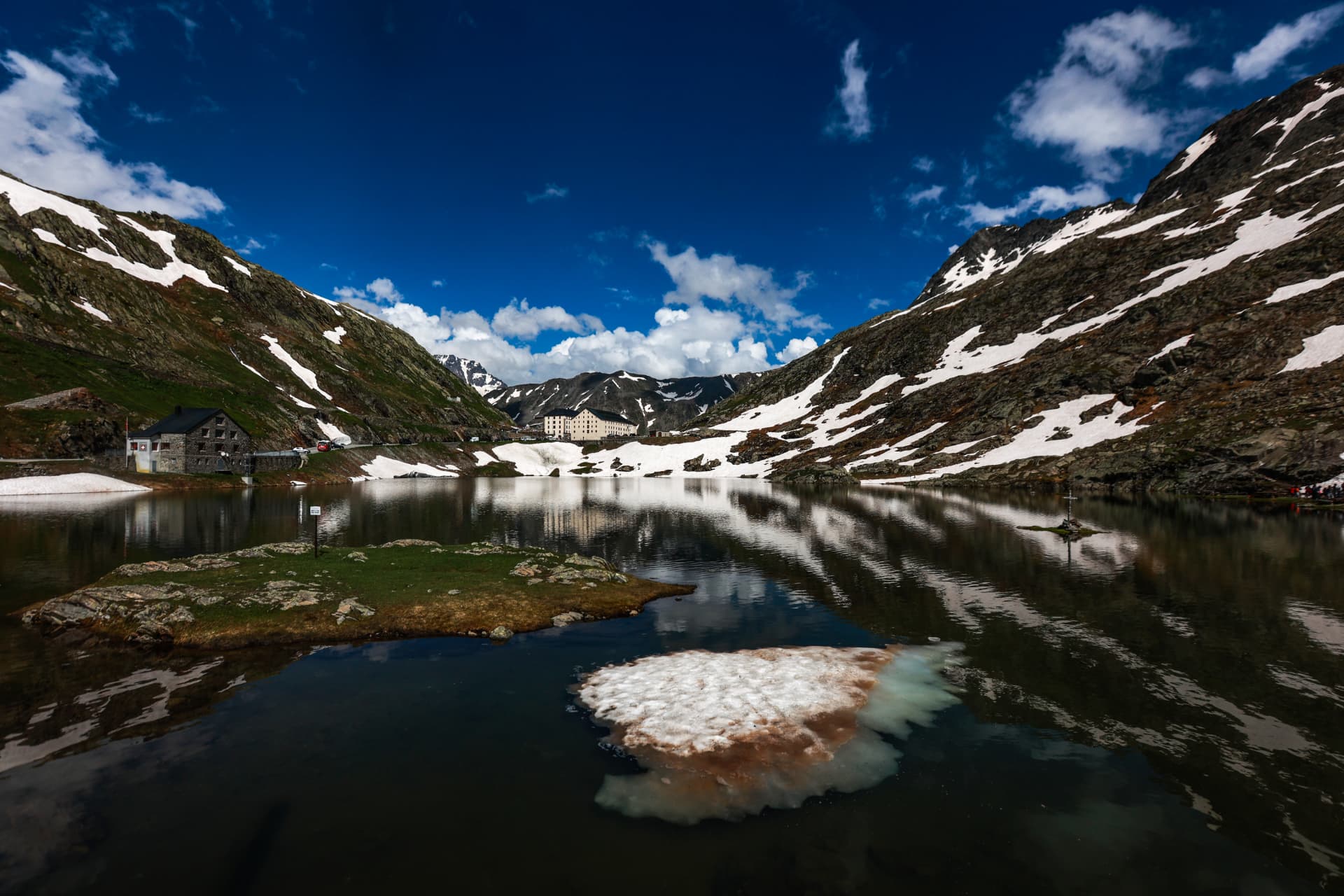 Der See auf dem Grossen Sankt Bernhard mit Schneescholle und Hospiz im Hintergrund