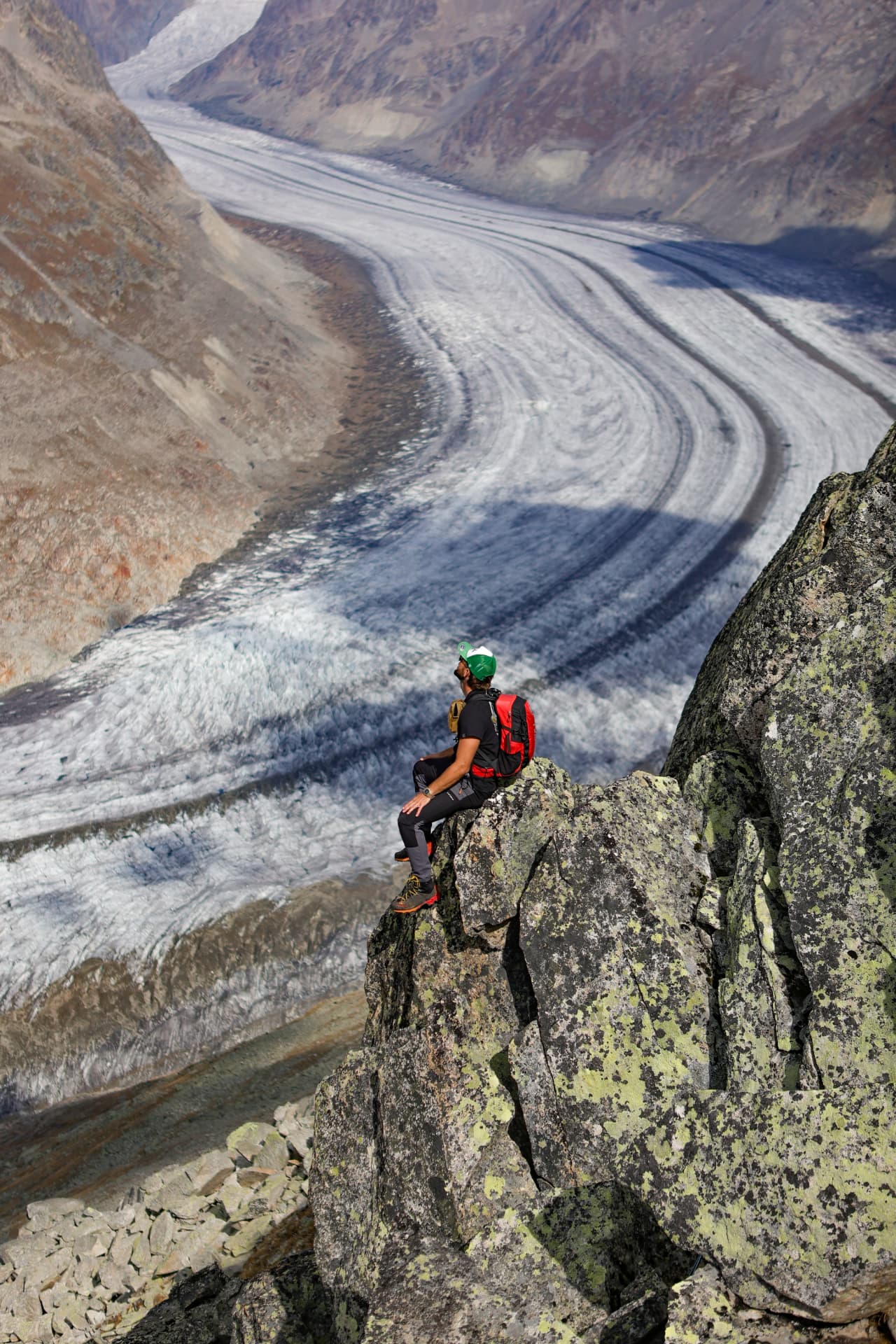 Wanderer auf einem Felsen hoch über dem Grossen Aletschgletscher