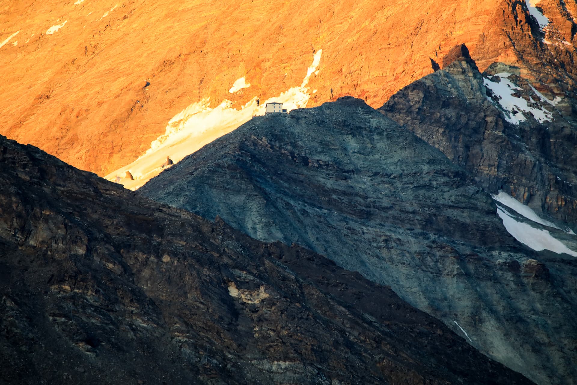 Hütte auf einem Felsrücken im Alpenglühen