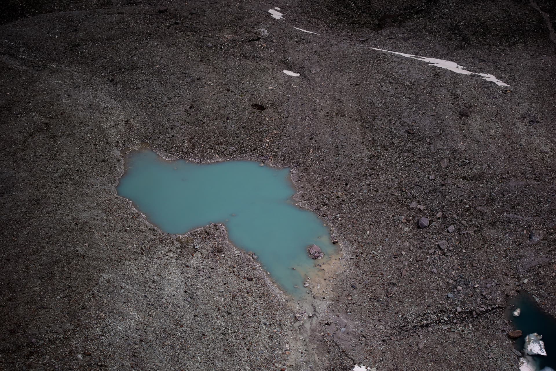 Türkisfarbener Schmelzwassertümpel auf grauer Gletschermoräne