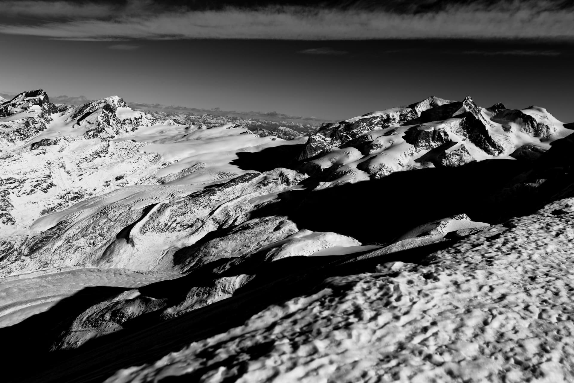Schwarzweisses Panorama von Gletscher und verschneiten Graten aus Gipfelhöhe
